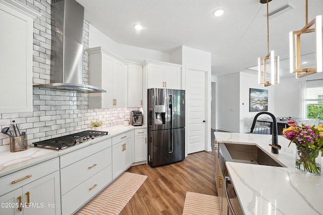 959 Crosswater Lake Dr, Ponte Vedra, FL 32081 - kitchen featuring appliances with stainless steel finishes, wall chimney exhaust hood, light wood-style floors, white cabinets, and backsplash
