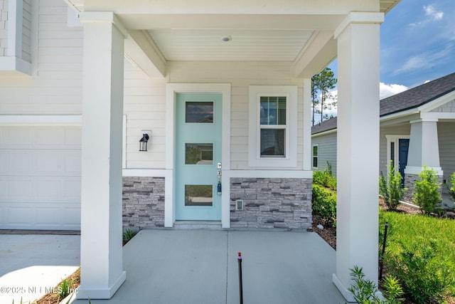 386 Whirlwind Pl, Saint Johns, FL 32095 - view of exterior entry featuring stone siding, a garage, and covered porch