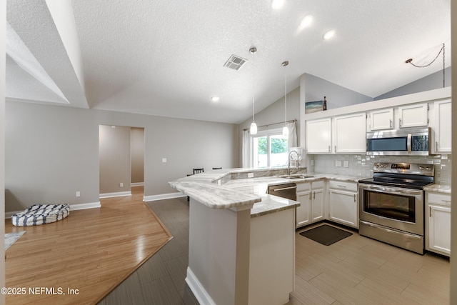4521 Deep River Way E, Jacksonville, FL 32224 - kitchen featuring stainless steel appliances, a peninsula, vaulted ceiling, tasteful backsplash, and white cabinets