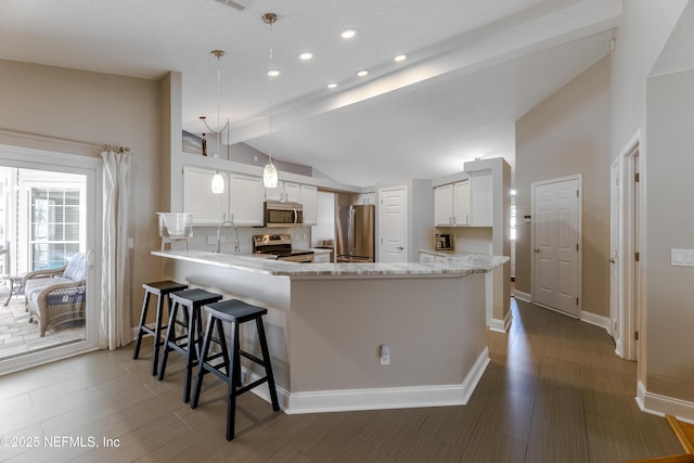 4521 Deep River Way E, Jacksonville, FL 32224 - kitchen featuring stainless steel appliances, vaulted ceiling, a peninsula, white cabinetry, and a breakfast bar area