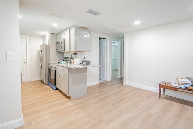 1841 W 11th St, Jacksonville, FL 32209 - kitchen featuring appliances with stainless steel finishes, light wood finished floors, white cabinets, light stone countertops, and recessed lighting