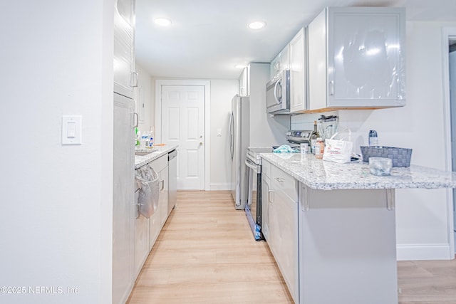 1841 W 11th St, Jacksonville, FL 32209 - kitchen with stainless steel appliances, light wood-style floors, light stone counters, recessed lighting, and white cabinets