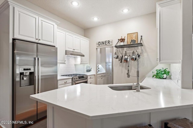 1060 Meadow View Ln, Saint Augustine, FL 32092 - kitchen with appliances with stainless steel finishes, under cabinet range hood, a peninsula, backsplash, and white cabinets