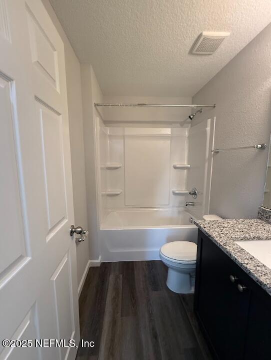 8045 Driggers St, Jacksonville, FL 32220 - bathroom featuring a textured ceiling, vanity, wood finished floors, and washtub / shower combination