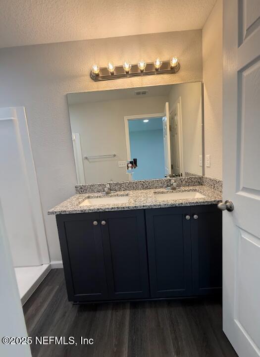 8045 Driggers St, Jacksonville, FL 32220 - full bathroom with wood finished floors, double vanity, and a textured ceiling