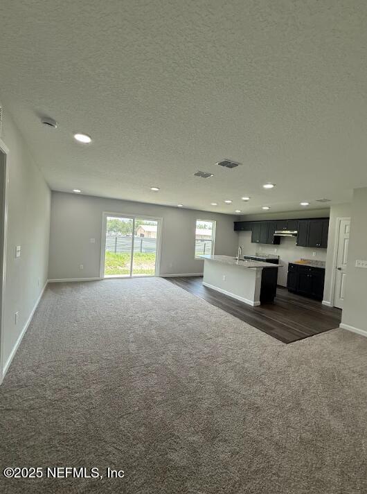 8045 Driggers St, Jacksonville, FL 32220 - unfurnished living room featuring dark carpet, recessed lighting, and a textured ceiling
