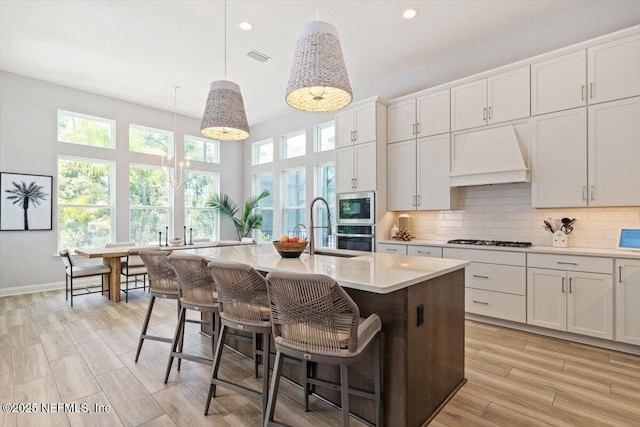 351 Palm Crst Dr, Ponte Vedra, FL 32081 - kitchen with custom exhaust hood, stainless steel appliances, light countertops, an island with sink, and decorative backsplash