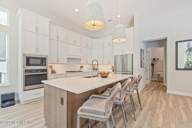 351 Palm Crst Dr, Ponte Vedra, FL 32081 - kitchen featuring appliances with stainless steel finishes, light countertops, light wood-style flooring, backsplash, and a kitchen bar