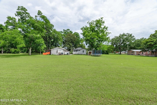 85215 Airplane Ln, Yulee, FL 32097 - view of green lawn with a trampoline and view of wooded area