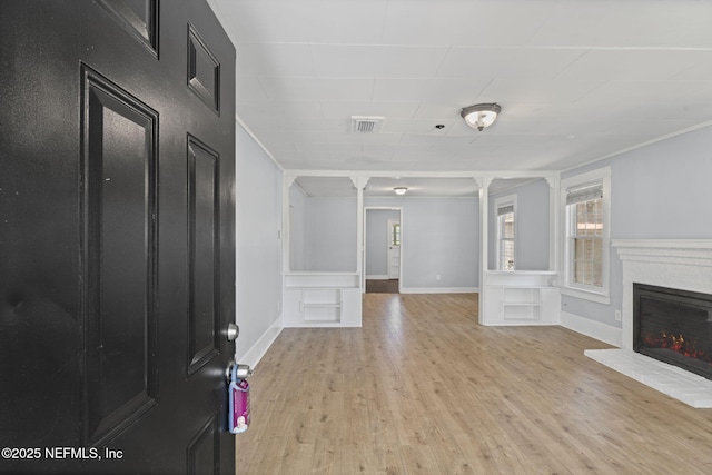85215 Airplane Ln, Yulee, FL 32097 - foyer featuring healthy amount of natural light, light wood-style flooring, a brick fireplace, a decorative wall, and wainscoting
