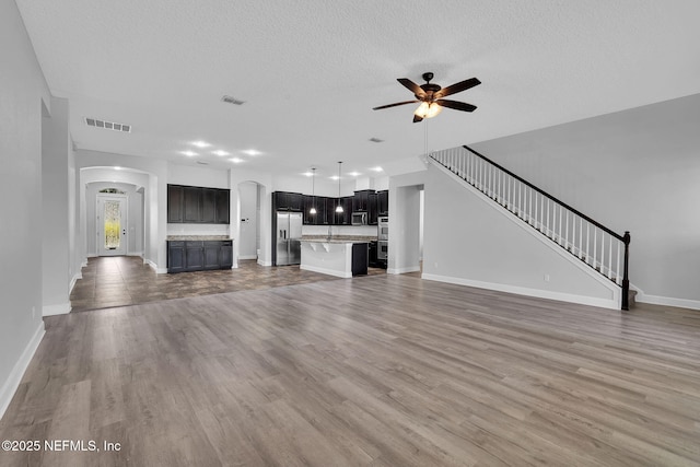 4431 Vista Point Ln, Orange Park, FL 32065 - unfurnished living room with arched walkways, a ceiling fan, wood finished floors, a textured ceiling, and stairs