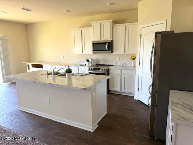 3432 Concord Ct, Green Cove Springs, FL 32043 - kitchen featuring appliances with stainless steel finishes, white cabinetry, dark wood-style flooring, a kitchen island with sink, and light countertops