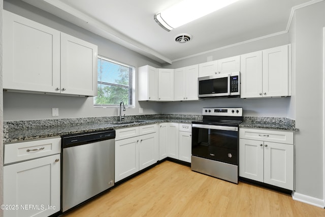 6552 Shady Oak Dr, Jacksonville, FL 32277 - kitchen with stainless steel appliances, light wood-style flooring, white cabinetry, crown molding, and dark stone counters