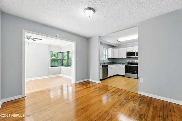 6552 Shady Oak Dr, Jacksonville, FL 32277 - kitchen with appliances with stainless steel finishes, white cabinetry, light wood-style flooring, ceiling fan, and a textured ceiling