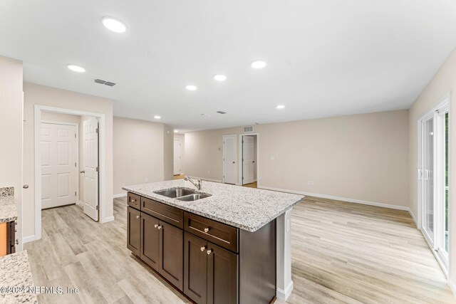 5428 Chenango Blvd, Jacksonville, FL 32254 - kitchen with light wood-style floors, an island with sink, dark brown cabinets, light stone countertops, and recessed lighting