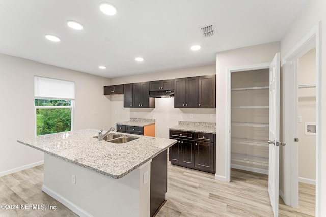 5428 Chenango Blvd, Jacksonville, FL 32254 - kitchen featuring under cabinet range hood, light wood finished floors, dark brown cabinets, a kitchen island with sink, and recessed lighting