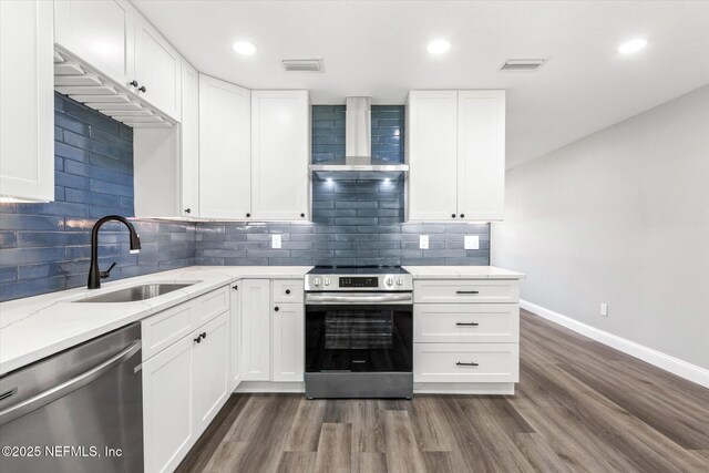 110 Pleasant Dr, East Palatka, FL 32131 - kitchen with appliances with stainless steel finishes, wall chimney range hood, dark wood-style flooring, light stone counters, and white cabinetry