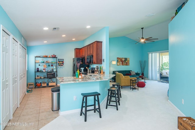 11890 Surfbird Cir Unit 42E, Jacksonville, FL 32256 - kitchen with black appliances, a ceiling fan, brown cabinetry, a breakfast bar area, and a peninsula