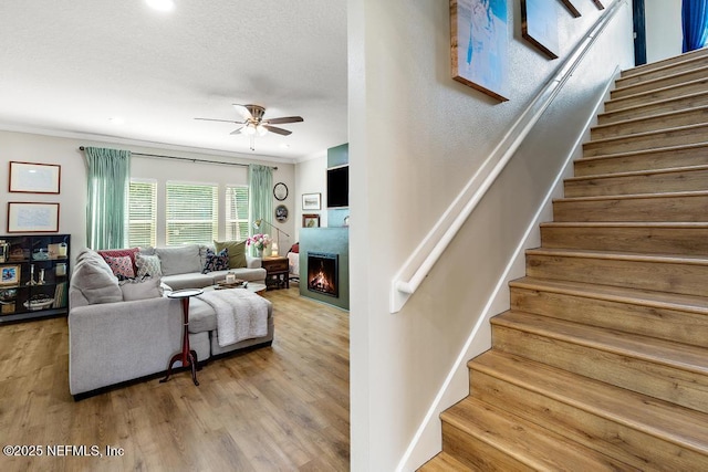 190 Colorado Springs Way, Saint Augustine, FL 32092 - living room featuring stairs, ornamental molding, ceiling fan, wood finished floors, and a warm lit fireplace