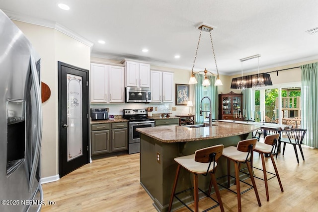 190 Colorado Springs Way, Saint Augustine, FL 32092 - kitchen featuring appliances with stainless steel finishes, crown molding, a kitchen island with sink, a breakfast bar, and light wood-style flooring