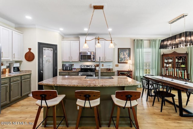 190 Colorado Springs Way, Saint Augustine, FL 32092 - kitchen featuring appliances with stainless steel finishes, ornamental molding, a center island with sink, light wood-style floors, and a breakfast bar area
