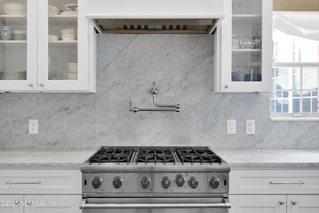 101 Royal Lagoon Ct, Ponte Vedra Beach, FL 32082 - kitchen with stainless steel range with gas stovetop, custom range hood, white cabinetry, glass insert cabinets, and light stone countertops