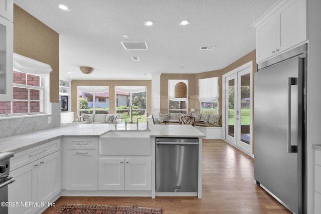 101 Royal Lagoon Ct, Ponte Vedra Beach, FL 32082 - kitchen with appliances with stainless steel finishes, french doors, a peninsula, white cabinetry, and light wood finished floors