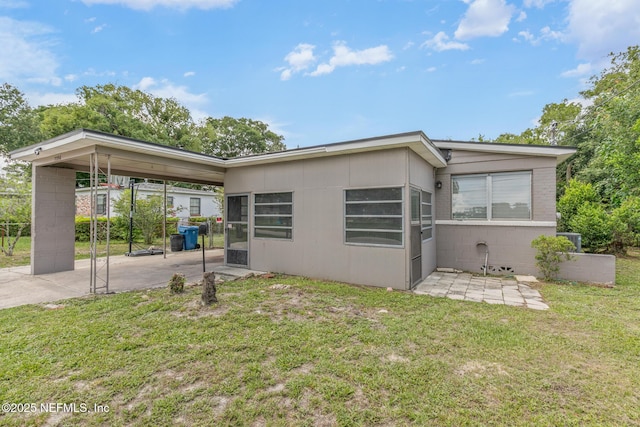 7314 Hielo Dr, Jacksonville, FL 32211 - view of front of property featuring an attached carport, a patio area, a front lawn, and concrete block siding