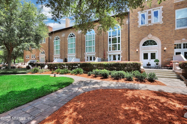 2525 College St Unit 1305, Jacksonville, FL 32204 - view of front facade with brick siding, a chimney, a front yard, and french doors