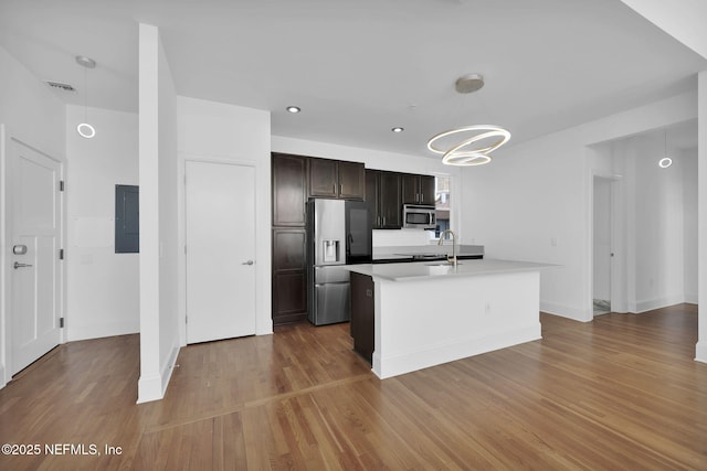 2525 College St Unit 1305, Jacksonville, FL 32204 - kitchen featuring appliances with stainless steel finishes, electric panel, light countertops, wood finished floors, and a kitchen island with sink