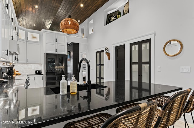 74 Sanford St, Saint Augustine, FL 32084 - kitchen featuring a kitchen bar, dark stone counters, wooden ceiling, white cabinetry, and a towering ceiling
