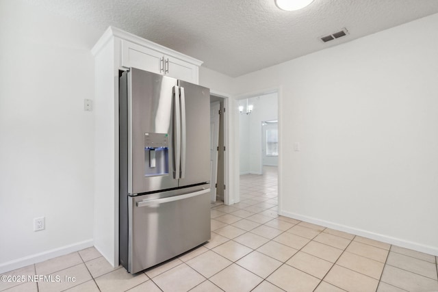 423 S Blvd, Macclenny, FL 32063 - kitchen with stainless steel fridge, a textured ceiling, light tile patterned floors, and white cabinets