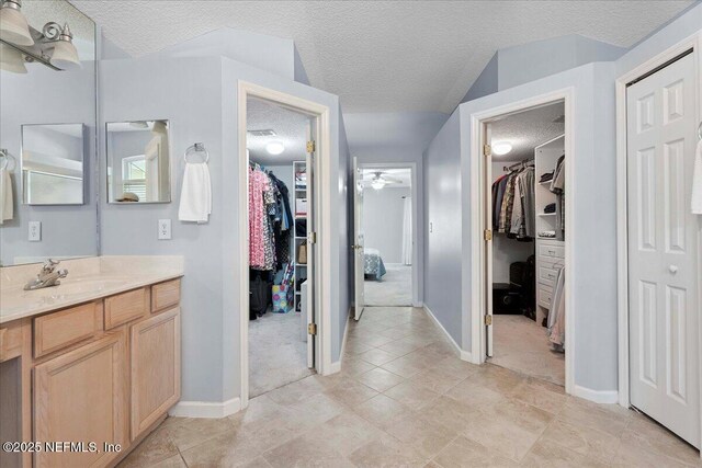 573 N Bridgestone Ave, Saint Johns, FL 32259 - bathroom featuring a walk in closet, a textured ceiling, vanity, and a ceiling fan