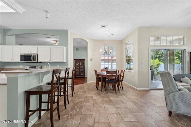 573 N Bridgestone Ave, Saint Johns, FL 32259 - dining area featuring a chandelier, plenty of natural light, arched walkways, and a textured ceiling