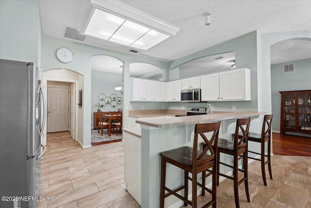 573 N Bridgestone Ave, Saint Johns, FL 32259 - kitchen featuring appliances with stainless steel finishes, a breakfast bar, white cabinets, light countertops, and a textured ceiling