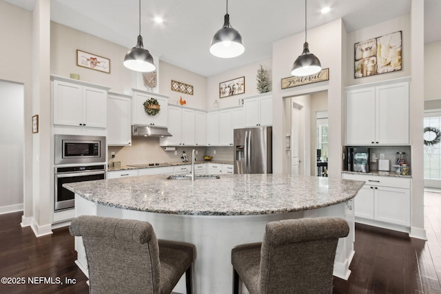 36501 Shortleaf Ave, Hilliard, FL 32046 - kitchen featuring appliances with stainless steel finishes, under cabinet range hood, a high ceiling, white cabinets, and a breakfast bar