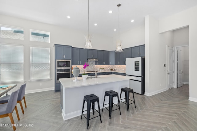 238 Courtney Chase Dr, Saint Augustine, FL 32092 - kitchen with appliances with stainless steel finishes, light countertops, a towering ceiling, a breakfast bar, and backsplash