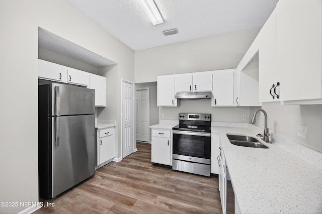 1359 Cove Landing Dr, Jacksonville, FL 32233 - kitchen featuring appliances with stainless steel finishes, under cabinet range hood, light countertops, white cabinetry, and light wood finished floors