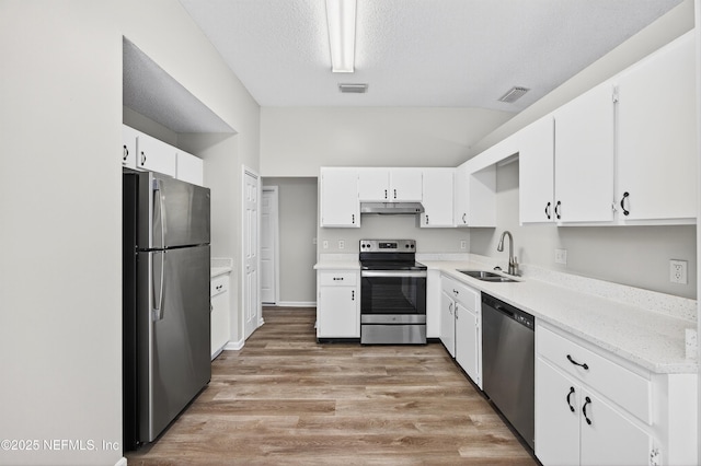 1359 Cove Landing Dr, Jacksonville, FL 32233 - kitchen featuring appliances with stainless steel finishes, under cabinet range hood, light wood finished floors, white cabinetry, and lofted ceiling