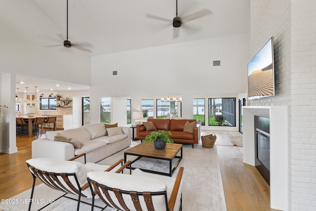 1823 N Lakeshore Dr, Fleming Island, FL 32003 - living room featuring high vaulted ceiling, a ceiling fan, a glass covered fireplace, wood finished floors, and a chandelier