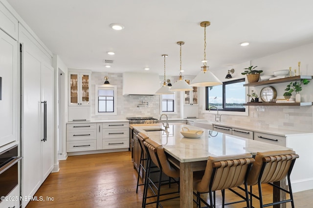 1823 N Lakeshore Dr, Fleming Island, FL 32003 - kitchen with a kitchen island with sink, a breakfast bar, backsplash, white cabinets, and stainless steel appliances