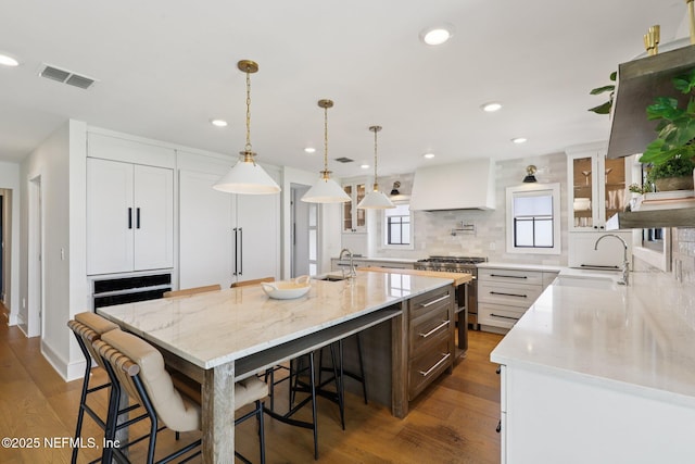1823 N Lakeshore Dr, Fleming Island, FL 32003 - kitchen with custom range hood, dark wood finished floors, a large island, glass insert cabinets, and backsplash