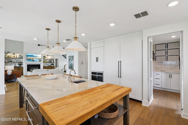 1823 N Lakeshore Dr, Fleming Island, FL 32003 - kitchen with a fireplace, wood finished floors, backsplash, recessed lighting, and white cabinetry