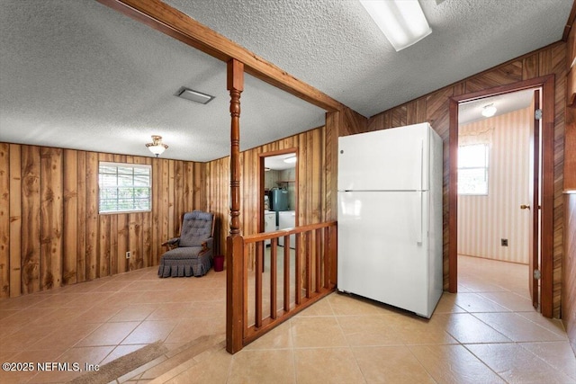 37206 Cypress Ln, Hilliard, FL 32046 - kitchen with freestanding refrigerator, wooden walls, a textured ceiling, light tile patterned floors, and washer / clothes dryer