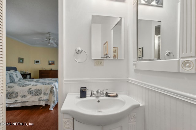 112 S 14th St, Fernandina Beach, FL 32034 - ensuite bathroom with wainscoting, ceiling fan, vanity, wood finished floors, and crown molding