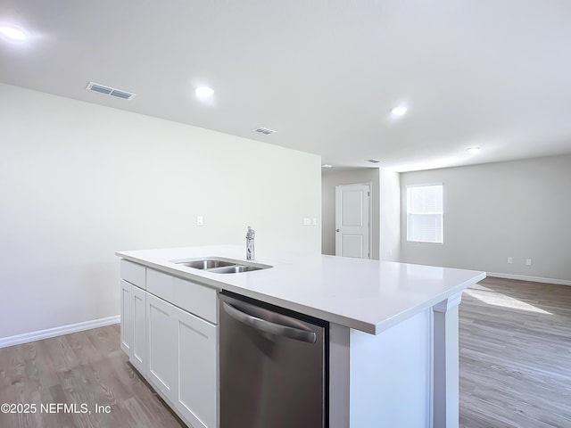 29 Wood Ash Ln, Palm Coast, FL 32164 - kitchen featuring stainless steel dishwasher, light wood finished floors, a center island with sink, light countertops, and white cabinets