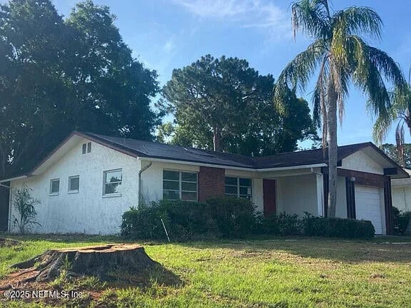819 Helmsman Way, Palm Harbor, FL 34685 - view of front of property featuring a garage, a front yard, and stucco siding
