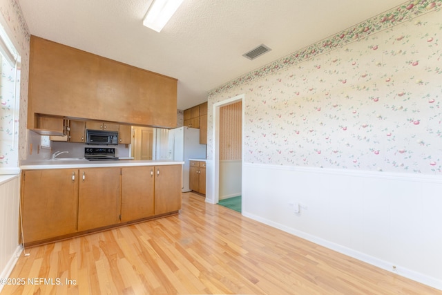 5042 Brighton Dr, Jacksonville, FL 32217 - kitchen with black appliances, wainscoting, a peninsula, light wood-type flooring, and light countertops