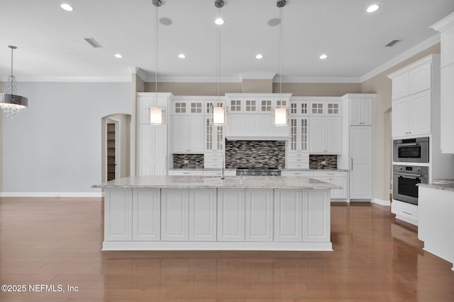 452 Deer Valley Dr, Ponte Vedra, FL 32081 - kitchen featuring arched walkways, tasteful backsplash, white cabinets, a large island with sink, and crown molding