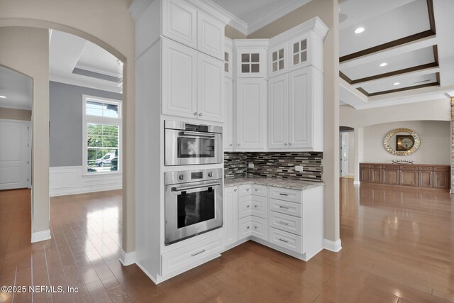 452 Deer Valley Dr, Ponte Vedra, FL 32081 - kitchen with arched walkways, crown molding, dark wood-style floors, light stone countertops, and white cabinetry